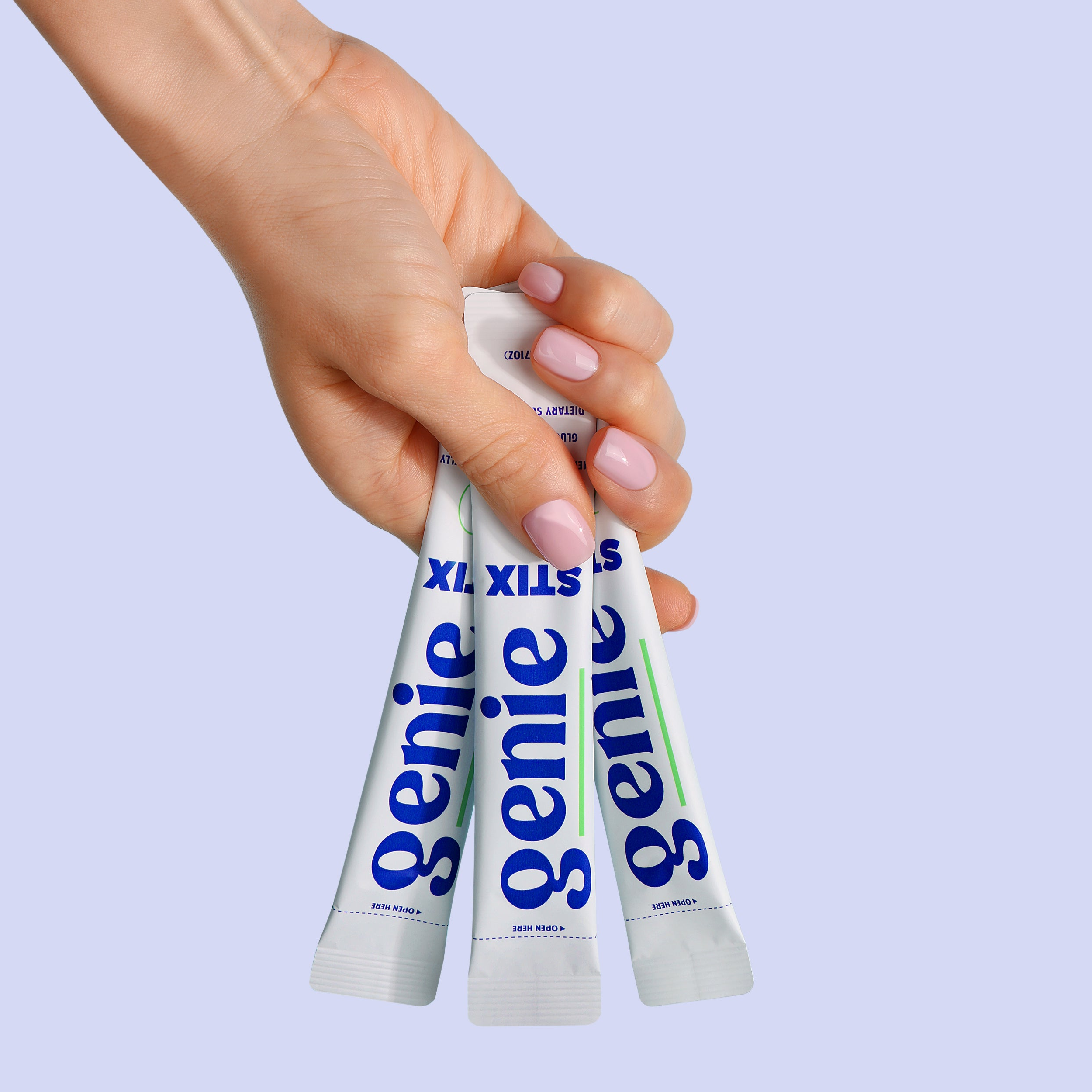 Hand holding three tubes of 'genie' product against a light purple background