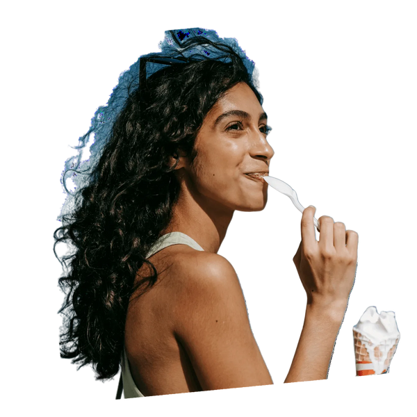 Woman eating ice cream with a cone and spoon on a white background
